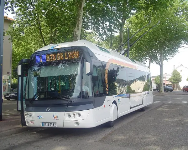 Trolleybus blanc à Lyon, prêt à partir. Les perches électriques sont visibles sur le toit.