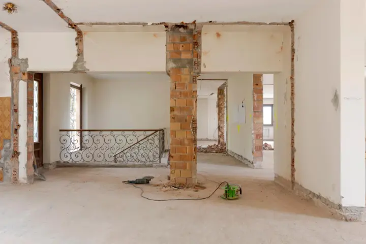 Intérieur en chantier, murs abattus, poutres apparentes. Les outils suggèrent une rénovation, pas une simple réhabilitation.