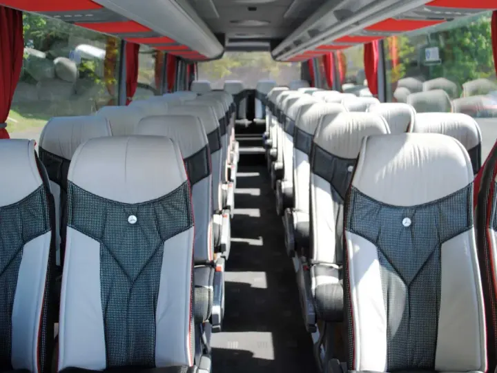 Intérieur d'un tour bus avec des sièges confortables et des rideaux rouges.