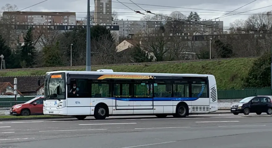 Le bus 11 de Limoges Couzeix roule sur la route, avec des immeubles en arrière-plan.
