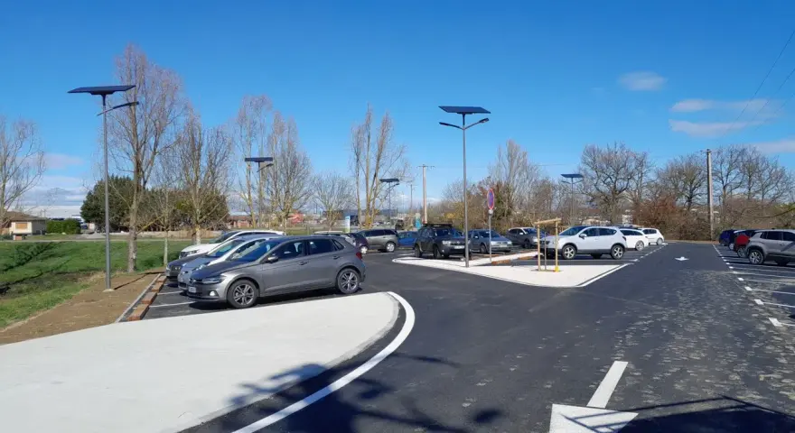 Stationnement de voitures dans une aire covoiturage Toulouse, éclairée par des lampadaires solaires sous un ciel bleu.
