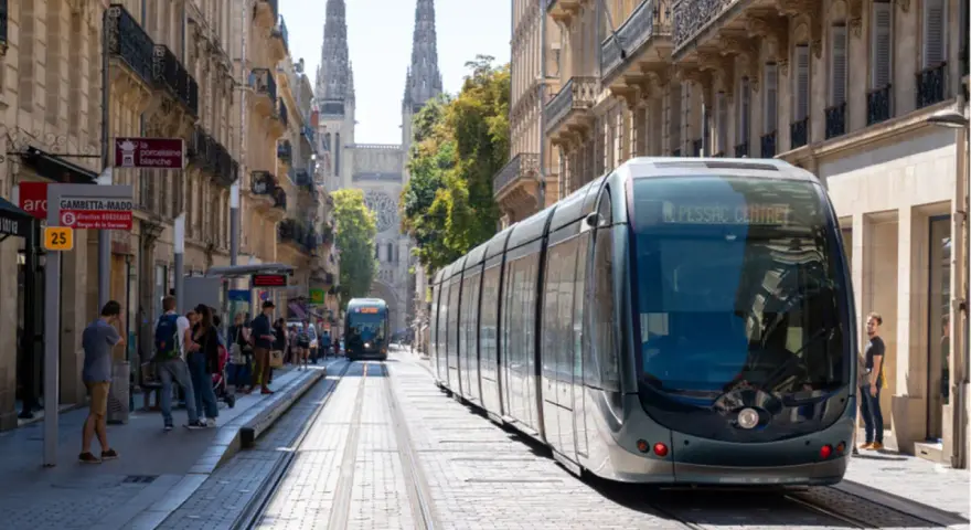 Un tramway moderne circule dans une rue pavée bordée de bâtiments anciens, témoignant du projet tramway urbain.