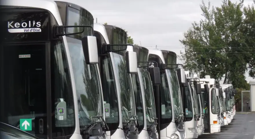 Une rangée de bus Keolis Val d'Oise stationnés, prêts pour le transport.