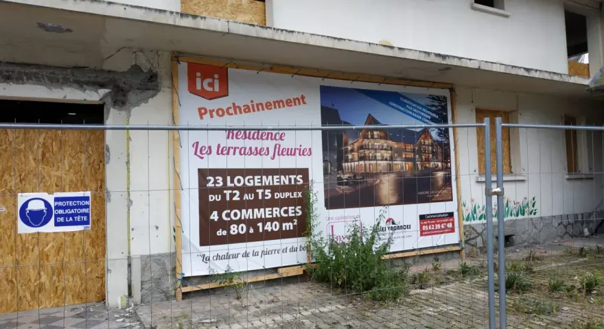 Panneau "Prochainement résidence Les terrasses fleuries" sur un bâtiment en démolition, signe de spéculation foncière.