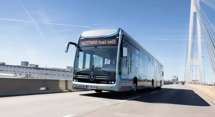eCitaro fuel cell, un bus articulé futuriste, roule sur une autoroute sous un ciel bleu. Sa fiche technique promet une mobilité propre.