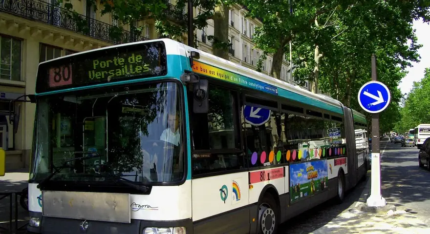 Autobus Renault Agora ligne 80, direction Porte de Versailles, circulant dans une rue bordée d'arbres à Paris.