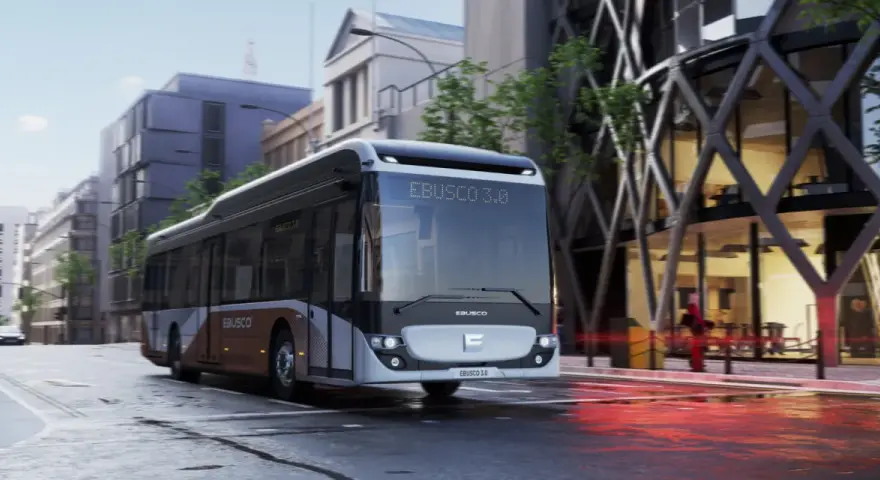 Un bus Ebusco 3.0 moderne circule dans une rue urbaine mouillée, reflétant les lumières de la ville.