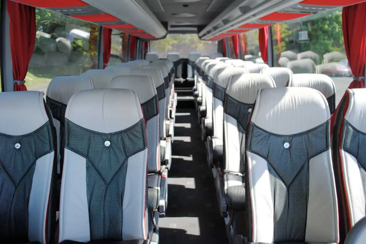 Intérieur d'un tour bus avec des sièges confortables et des rideaux rouges.