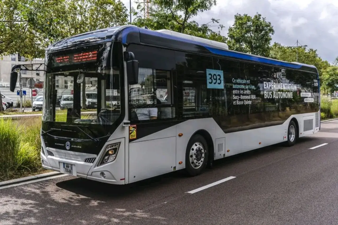 Un bus autonome expérimental circule sur une route, arborant le numéro 393 et des informations sur son parcours.