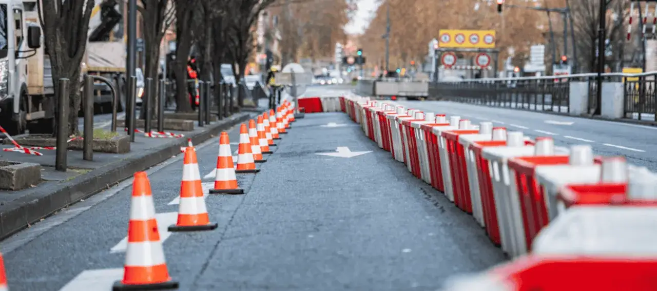 Cones et barrières de sécurité délimitent une voie sur une route, signalant des travaux du service voirie.