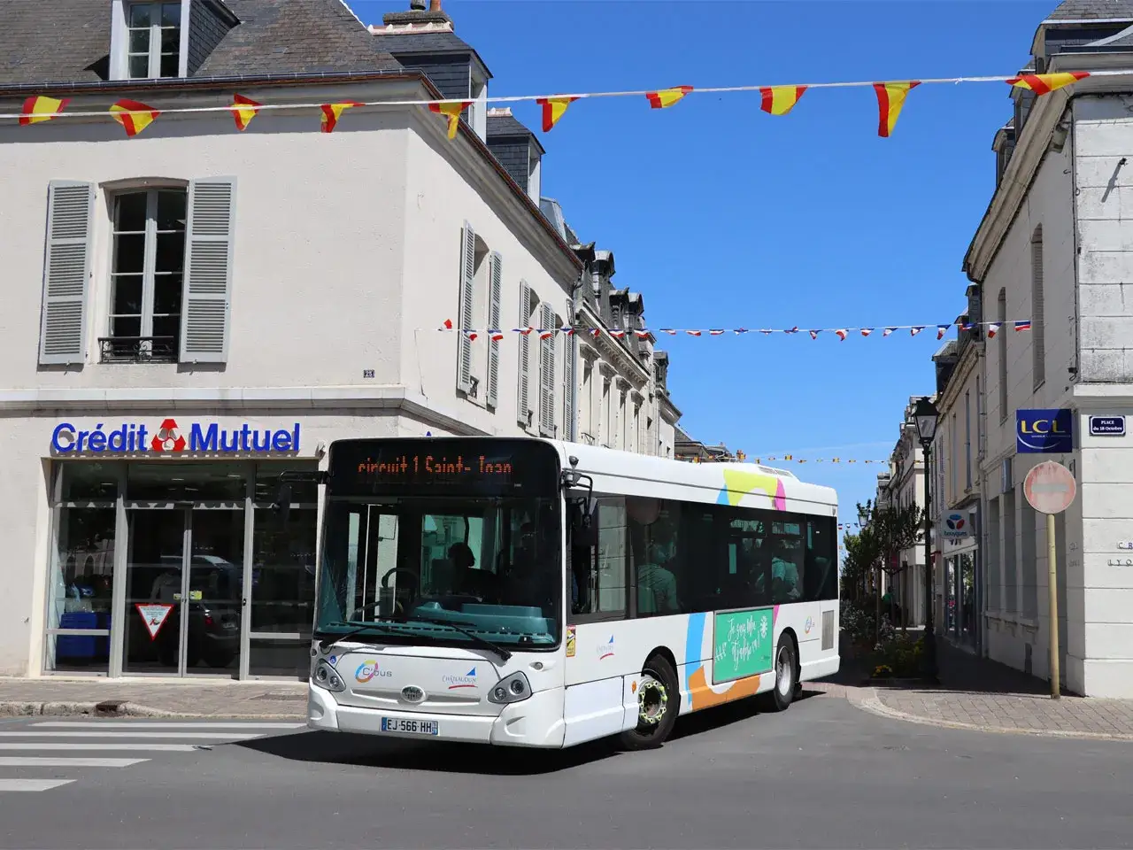 Un bus blanc circule dans une rue de Ch&acirc;teaudun. L'horaire du bus est affich&eacute; sur le pare-brise.