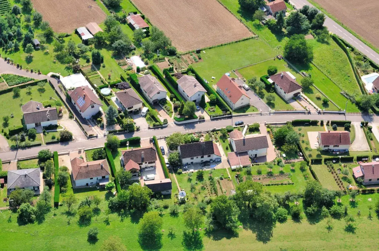 Vue aérienne d'un lotissement résidentiel en France, illustrant l'étalement urbain avec des maisons individuelles et des jardins.