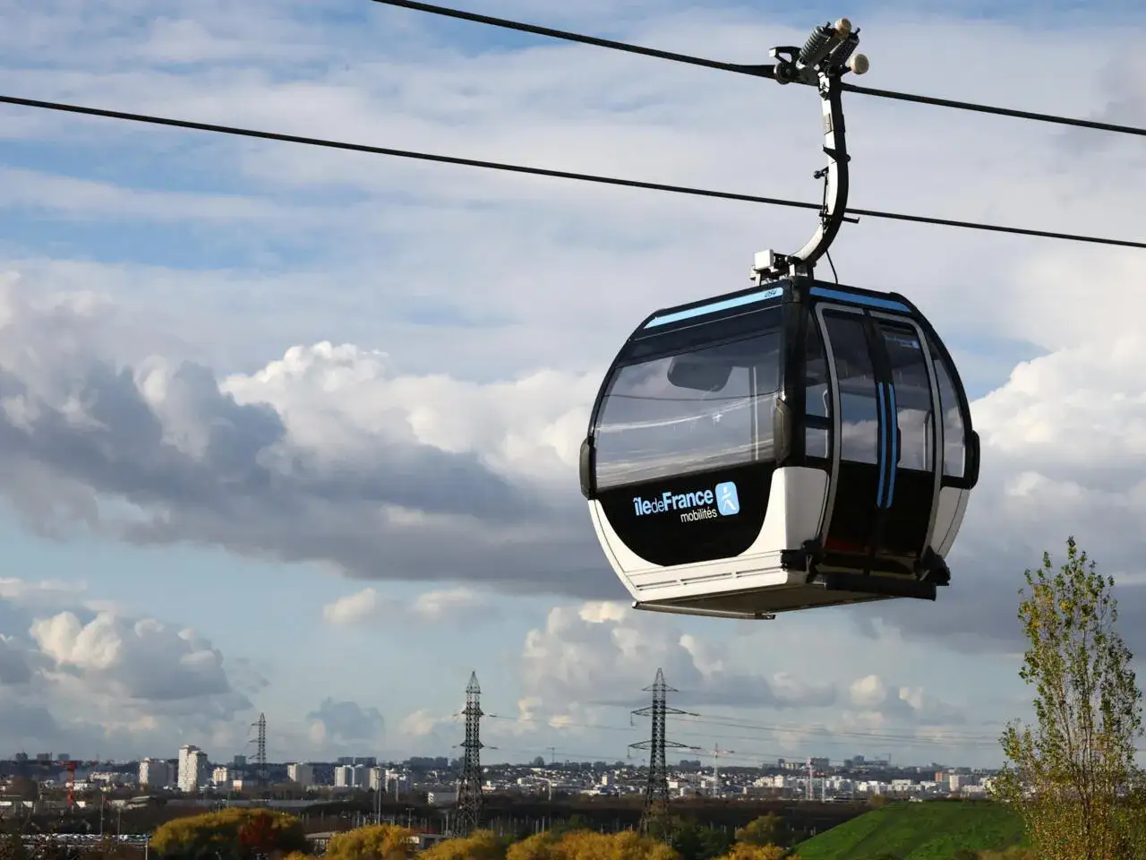 Cabine de t&eacute;l&eacute;ph&eacute;rique urbain en France, survolant un paysage urbain sous un ciel nuageux.