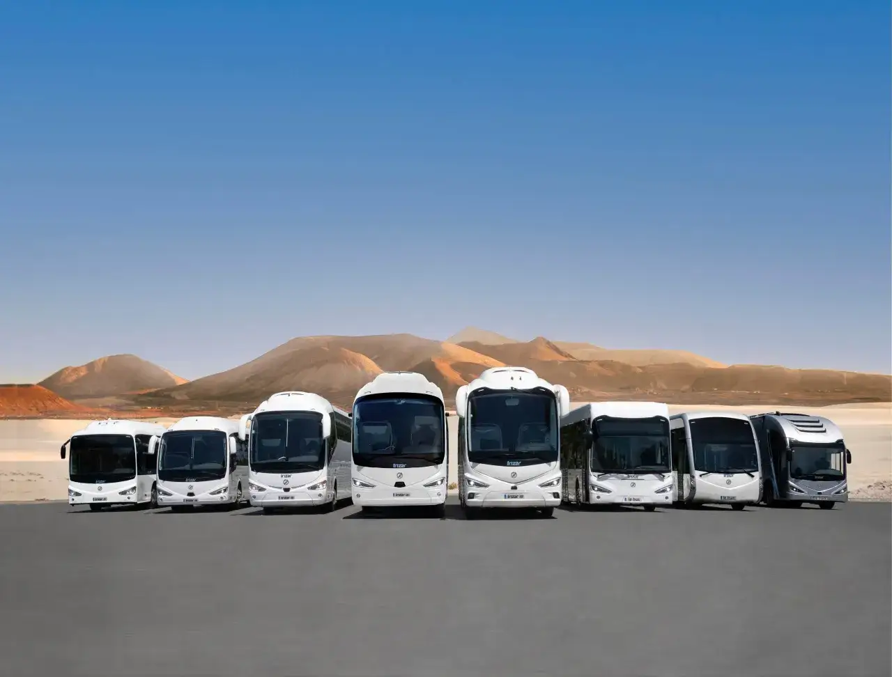 Une flotte de bus blancs align&eacute;s dans un paysage d&eacute;sertique. Le poids d'un bus peut varier consid&eacute;rablement selon sa taille et sa configuration.