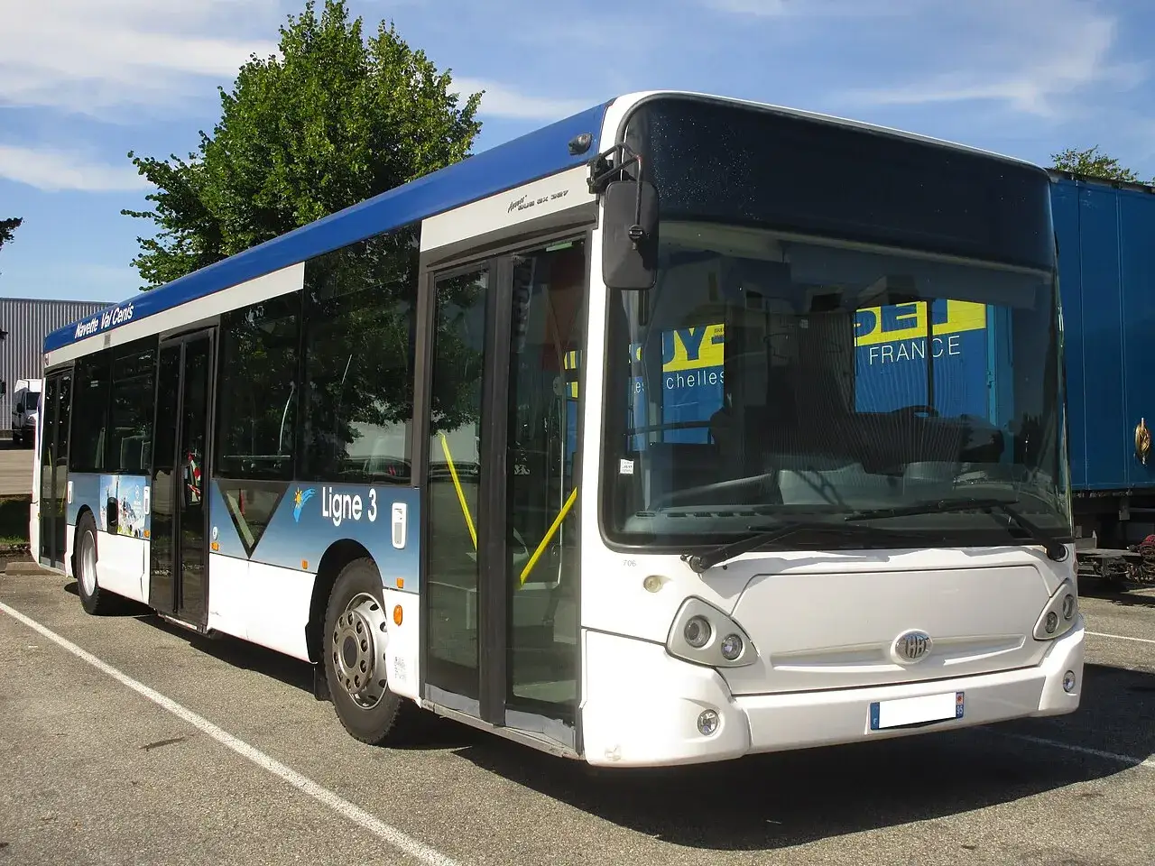 Un bus Heuliez GX 327 blanc et bleu, ligne 3, stationn&eacute; sur un parking.