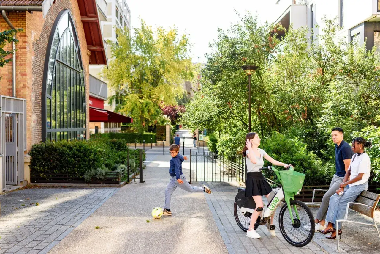 Un garçon joue au foot, une jeune femme est sur un vélo, et un couple discute. Une scène de vie animée qui illustre l'animation du territoire.