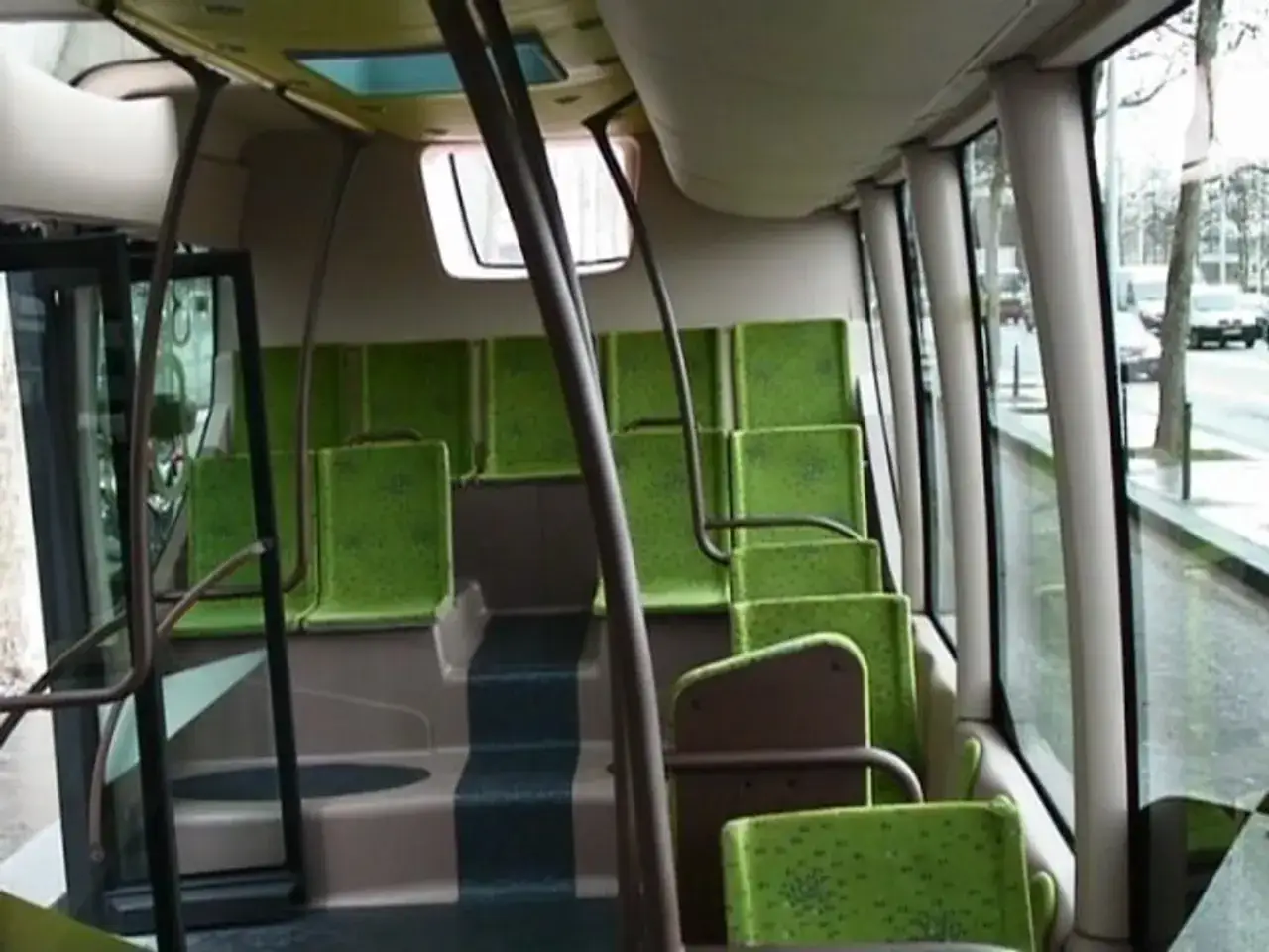 Intérieur d'un bus RATP avec des sièges verts vifs. Les marches sont sombres, contrastant avec les sièges. Dehors, la rue est visible à travers les grandes fenêtres.