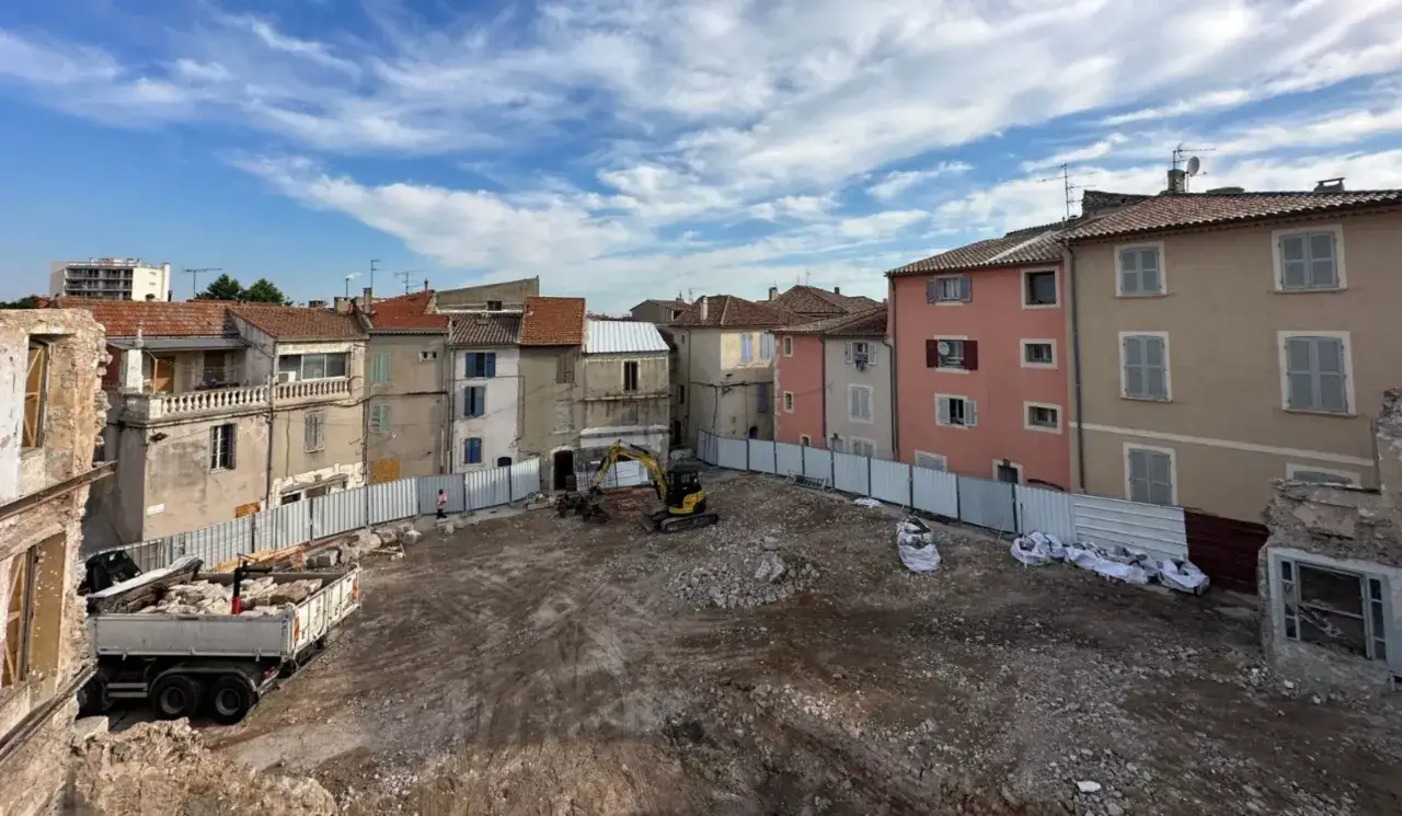 Chantier de démolition, une pelle mécanique et un camion sont présents. Ce site illustre la différence entre réhabilitation et rénovation.