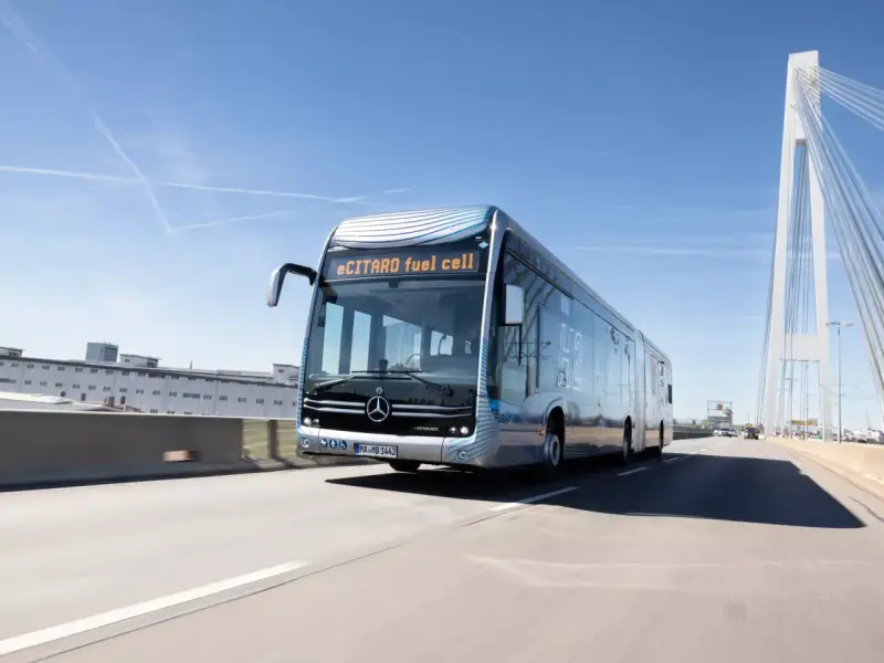 eCitaro fuel cell, un bus articulé futuriste, roule sur une autoroute sous un ciel bleu. Sa fiche technique promet une mobilité propre.